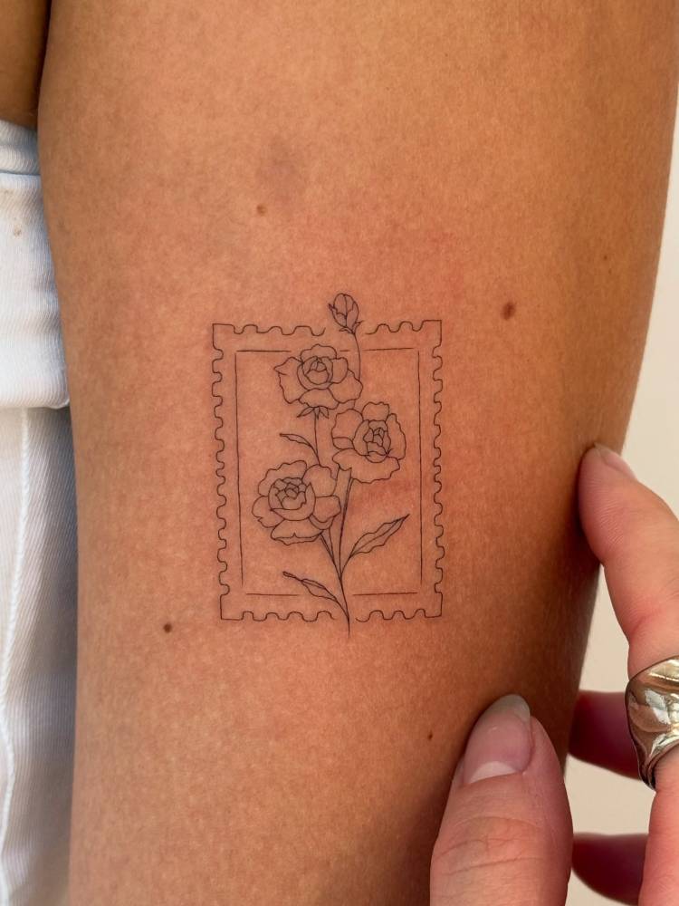 Fine line style rose stamp tattoo done on the upper arm.