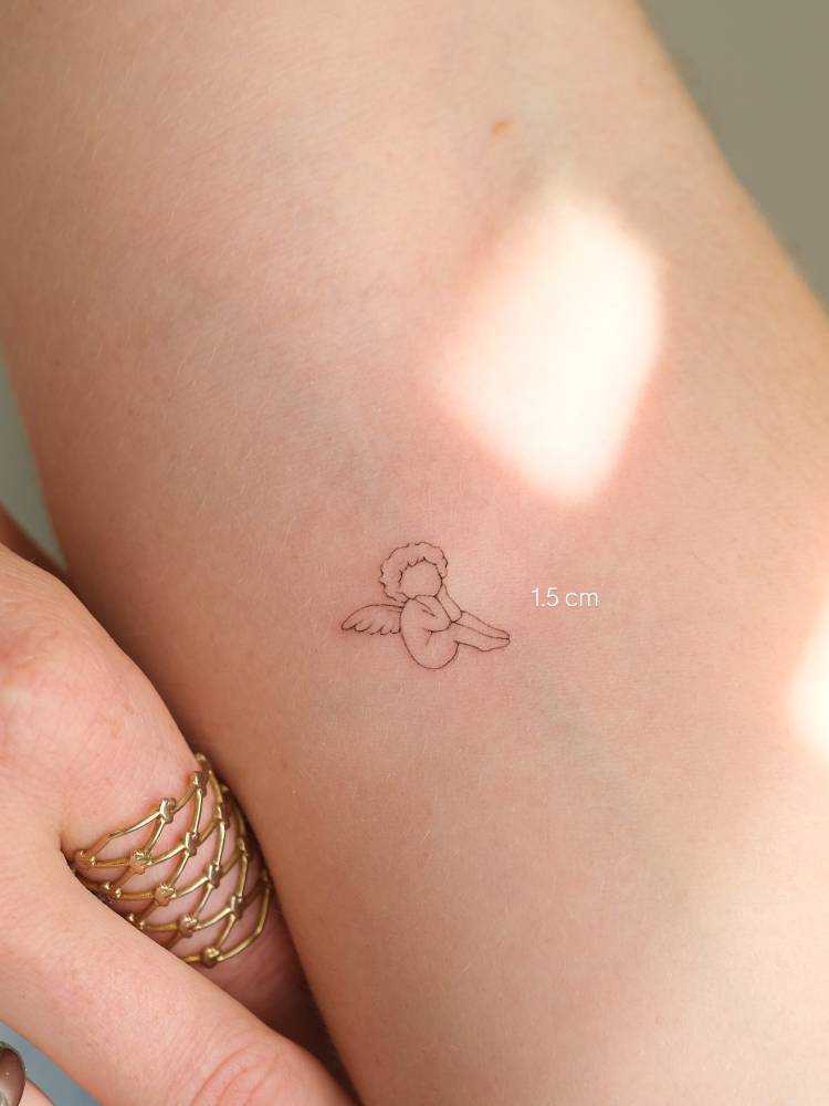 Tiny minimalistic cherub tattoo located on the inner forearm.