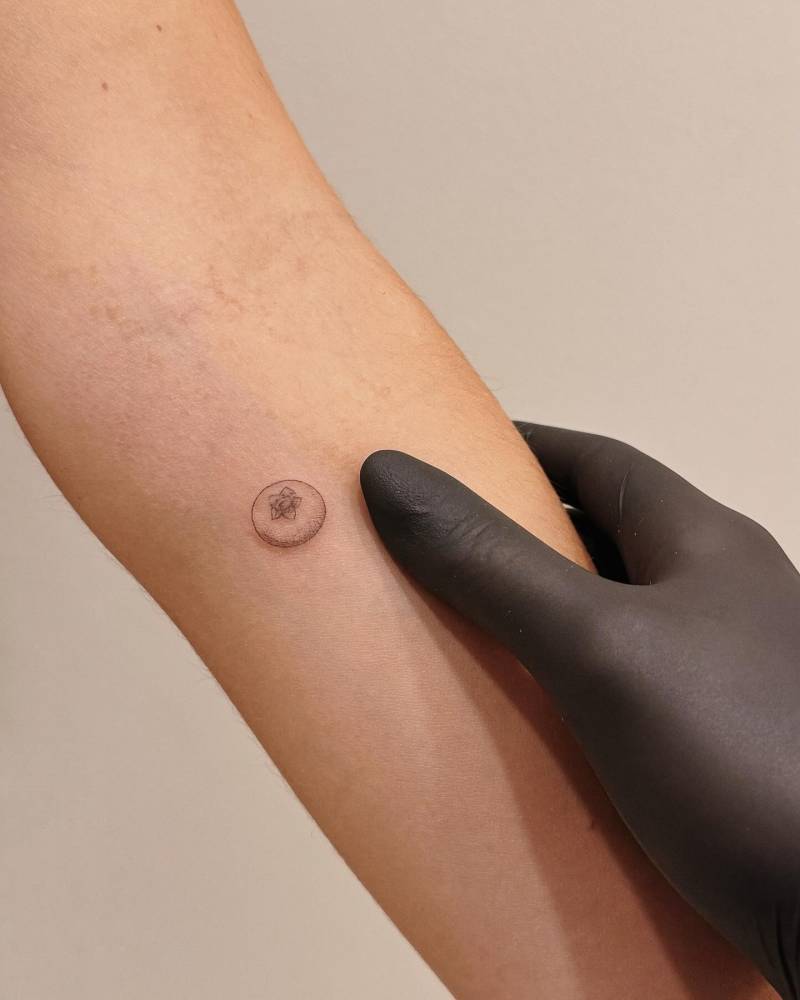 Tiny blueberry tattoo done on the inner forearm, illustrative style.