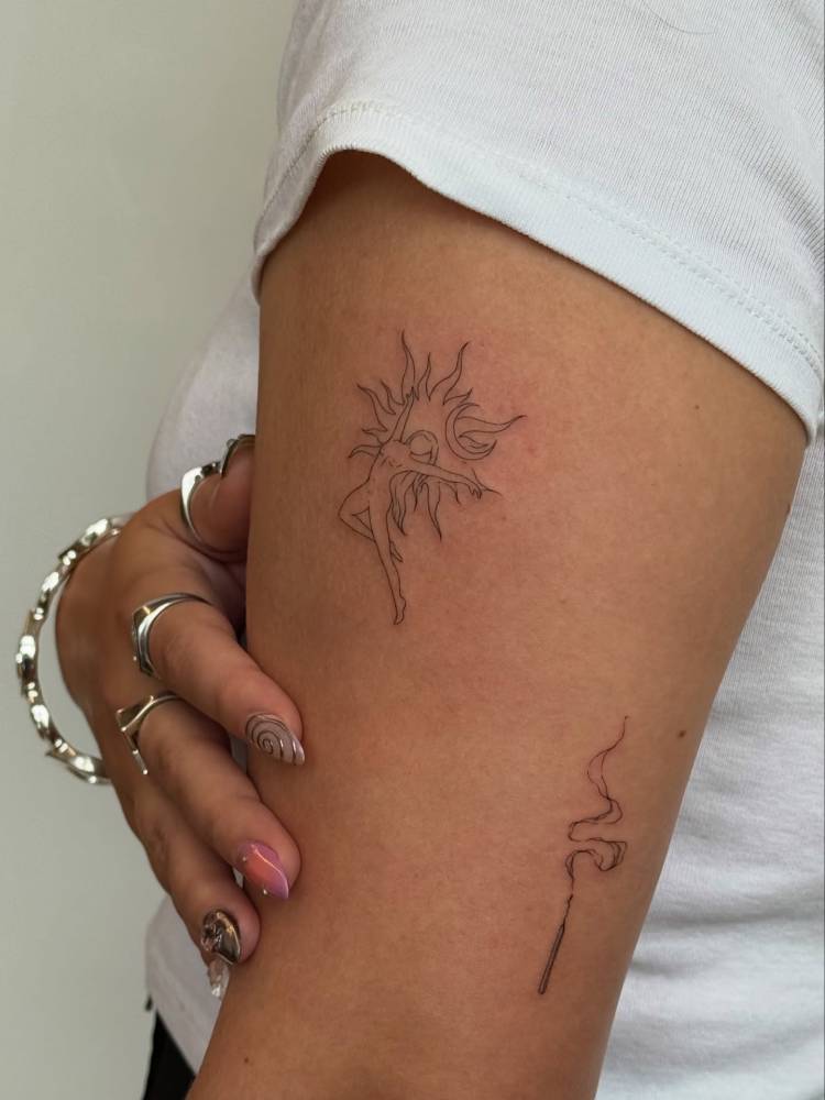 Nude dancer and sun tattoo located on the upper arm.