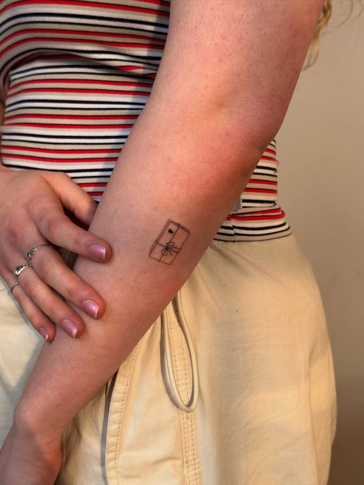 Love letter tattoo in fine line style placed on the forearm.