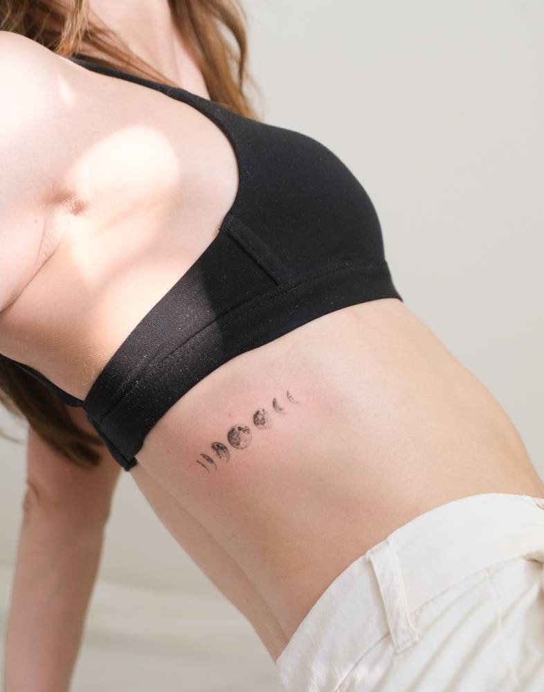 Single needle moon phases tattoo located on the rib.