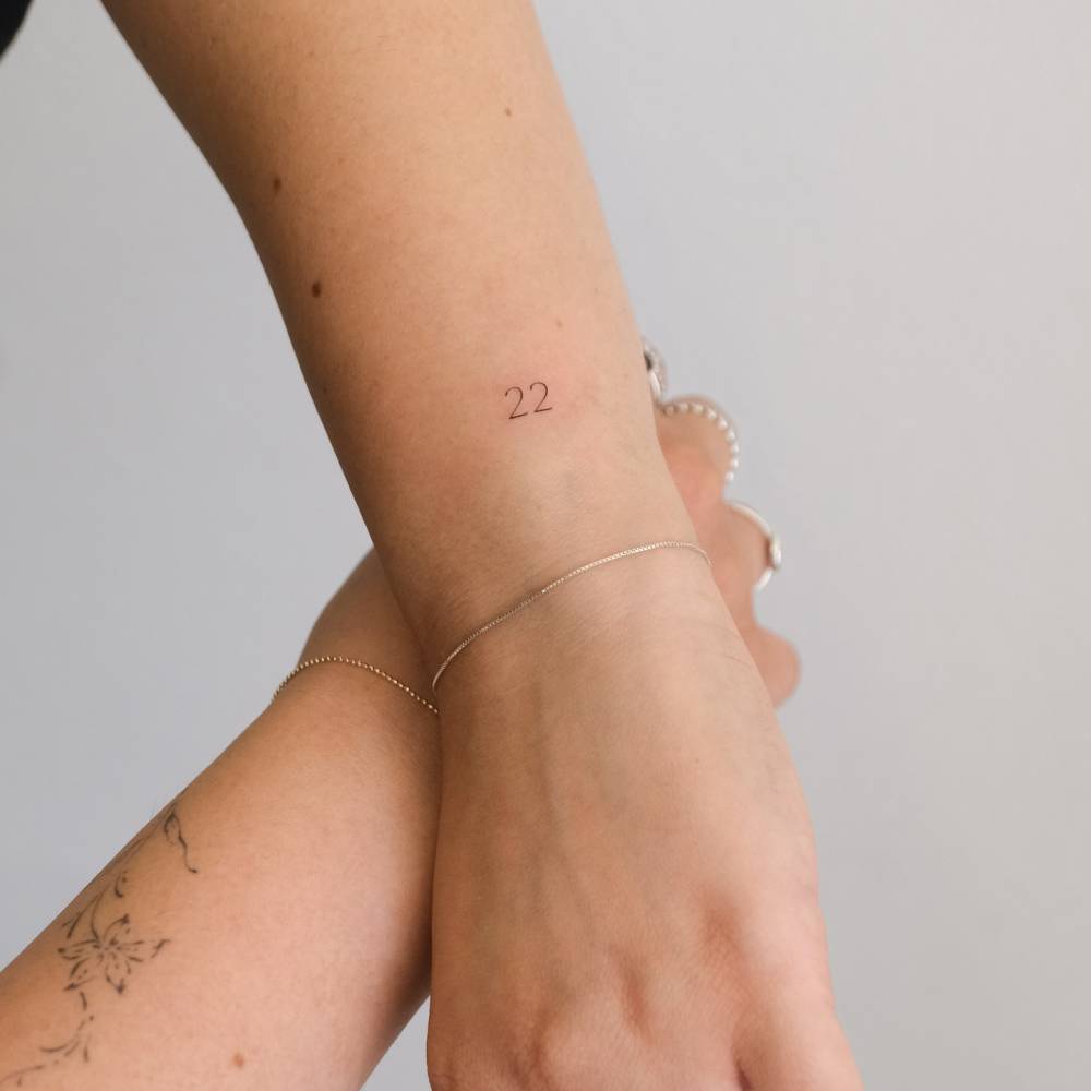 Lettering tattoo of the number "22" located on the wrist.