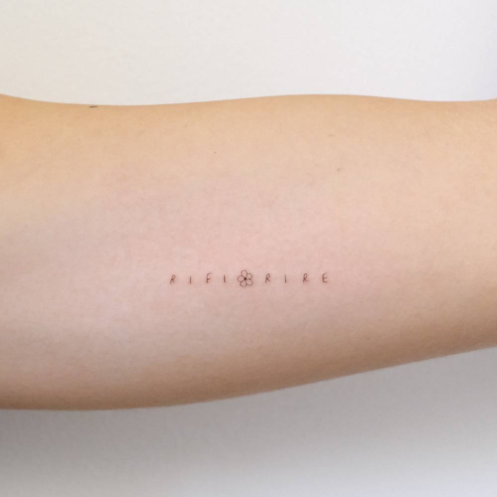 Word "rifiorire" lettering tattoo located on the inner arm.