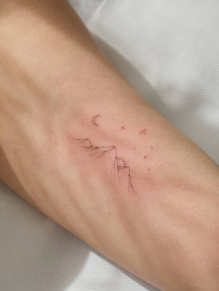 Single needle mountain sunset tattoo located on the inner arm.