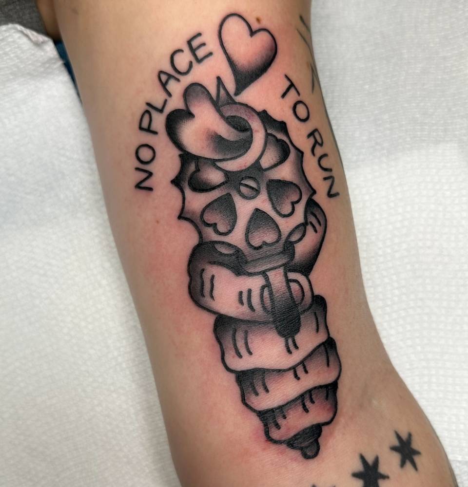 Revolver tattooed on the inner arm, done in traditional style.