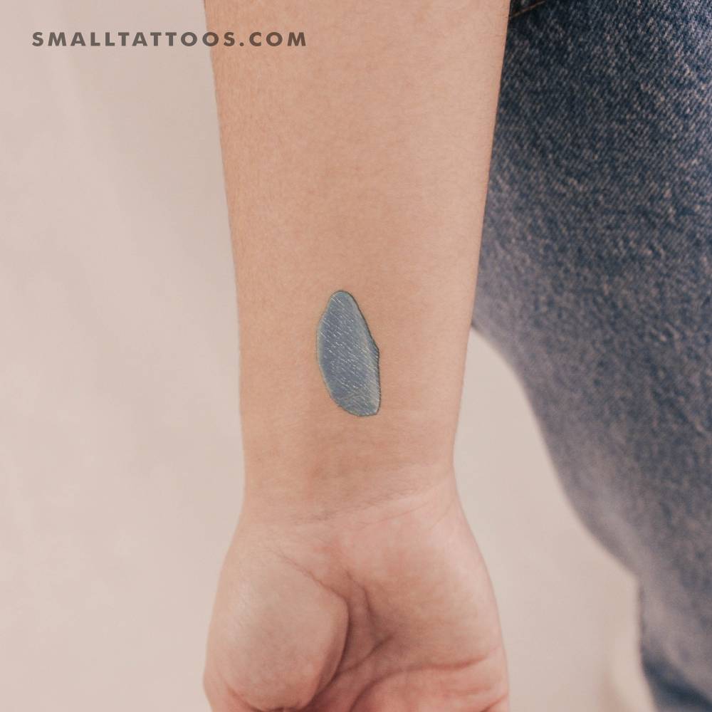 Turquoise brush stroke temporary tattoo located on the wrist.