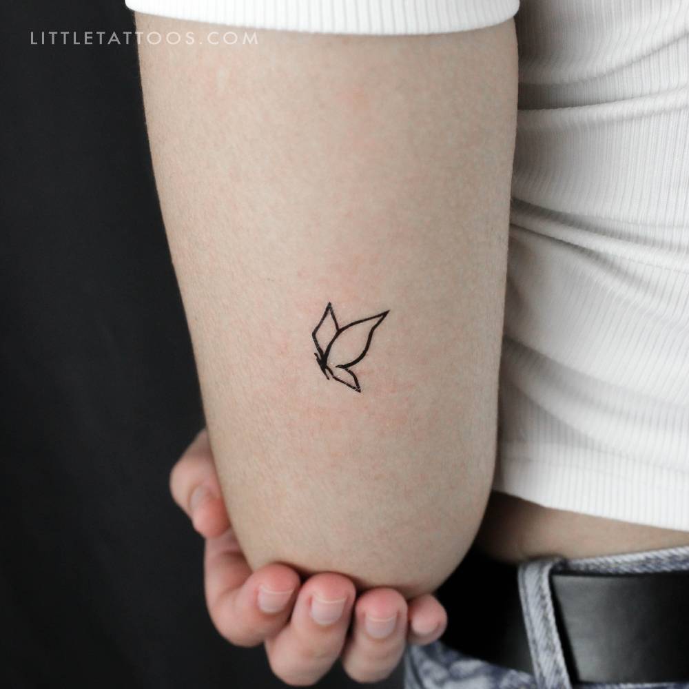 Minimalist flying butterfly temporary tattoo located on the tricep.