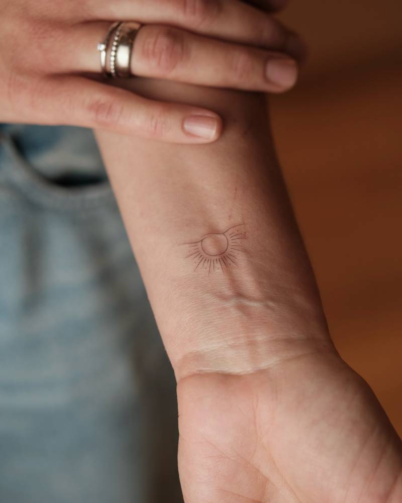 Fine line style sunset tattoo placed on the wrist.