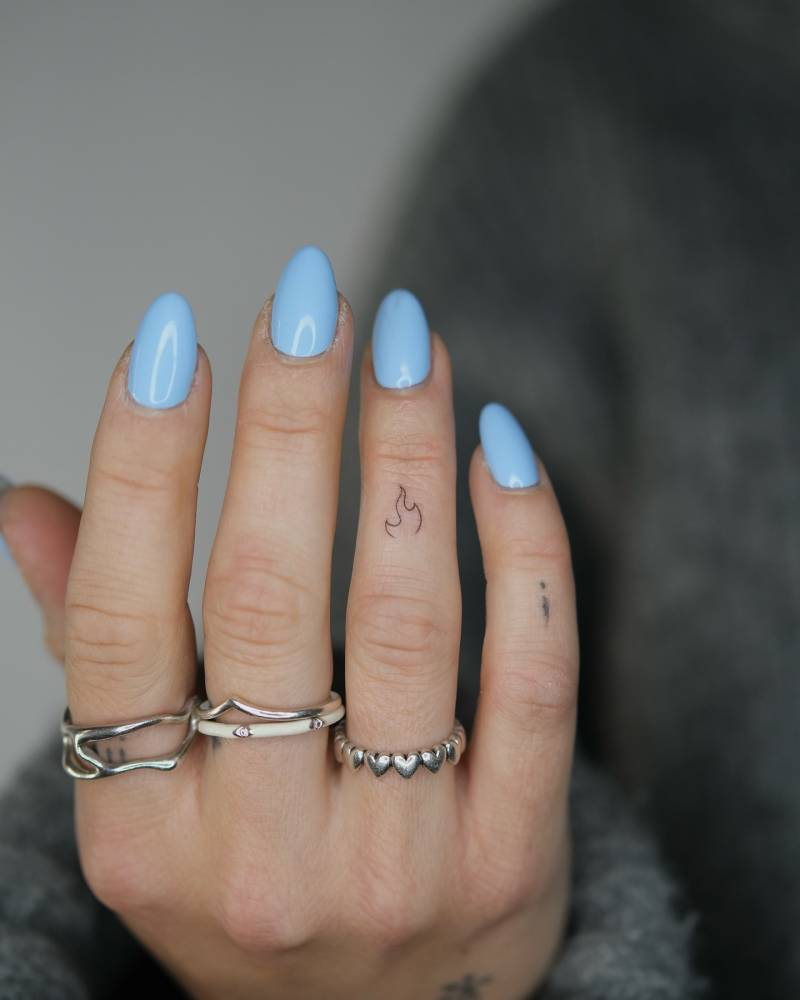Tiny minimalistic fire tattoo located on the finger.