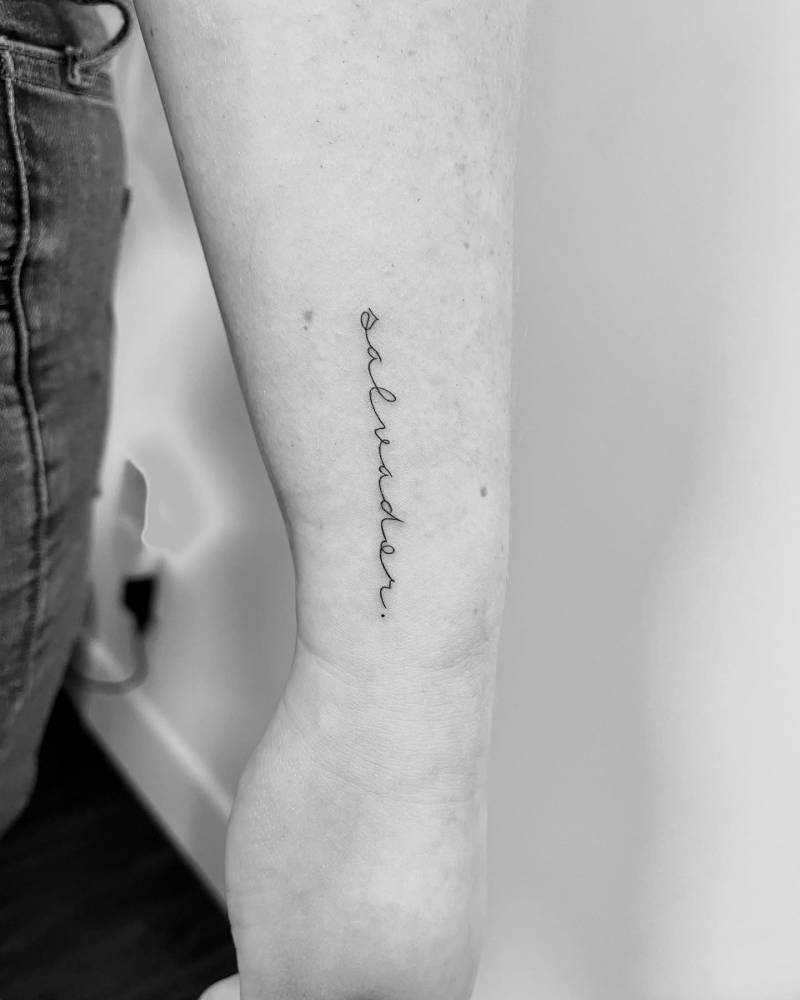 Handwritten lettering tattoo that says "salvador" located on the wrist.