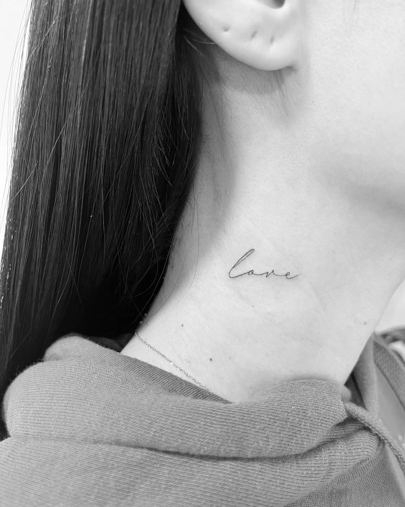 Handwritten lettering tattoo of the word "love" placed on the neck.