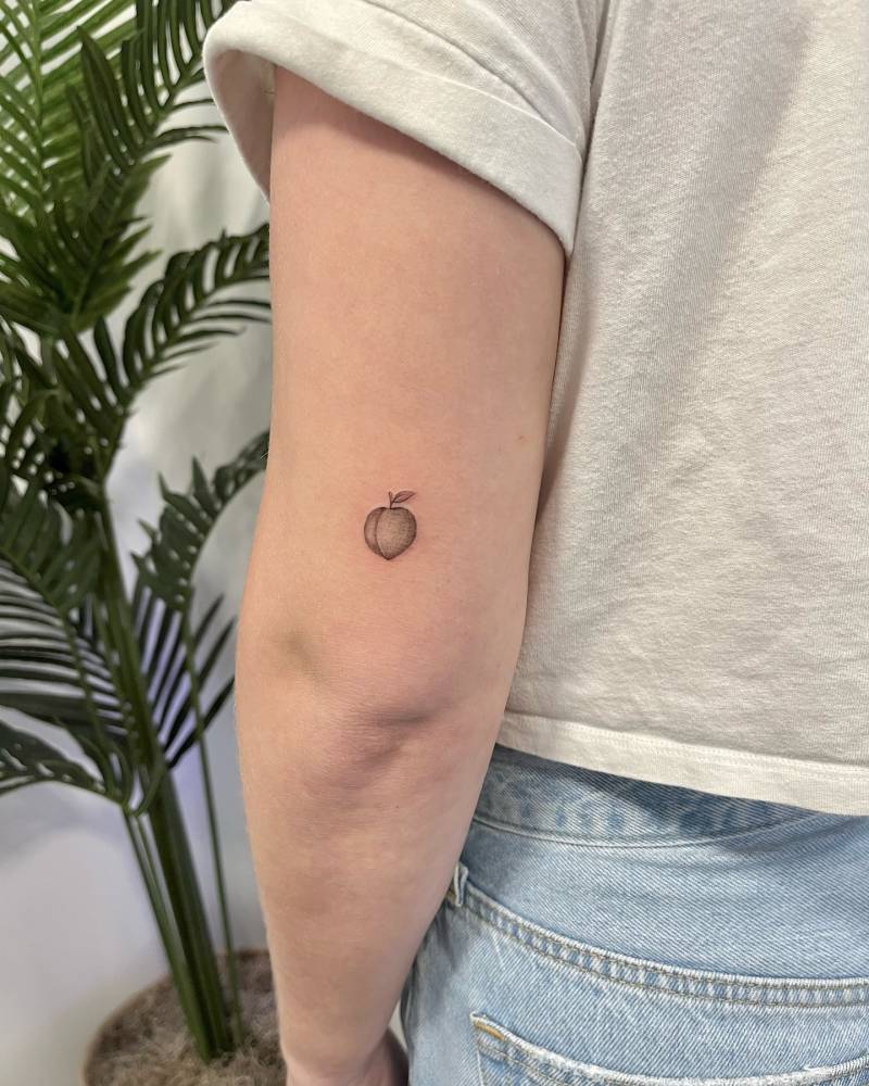 Tiny peach tattoo placed on the tricep, done in illustrative style.