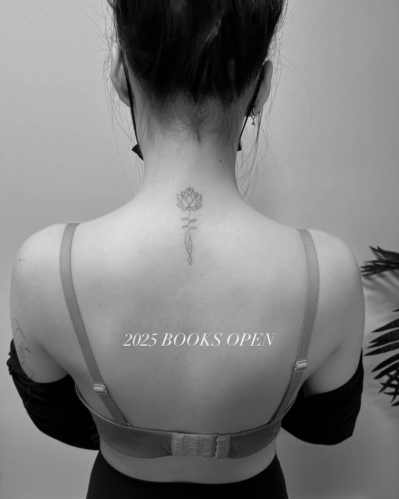 Fine line style lotus unalome tattoo placed on the upper back.