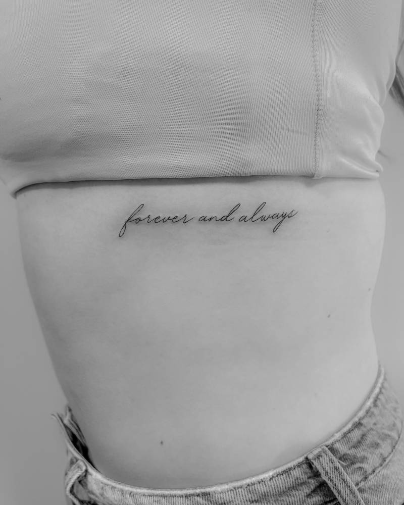 "Forever and always" lettering tattoo located on the rib.