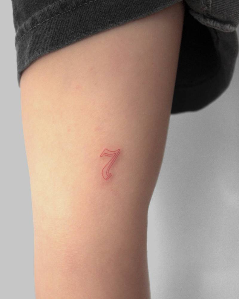 Red number "7" tattoo in gothic font located on the inner arm.