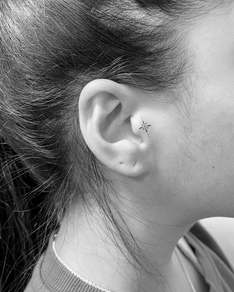 Tiny minimalistic ornament tattooed on the ear.