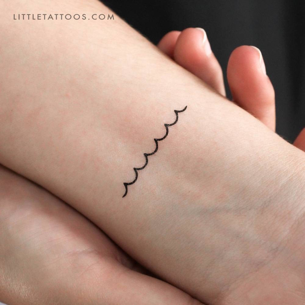 Minimalist waves temporary tattoo placed on the wrist.
