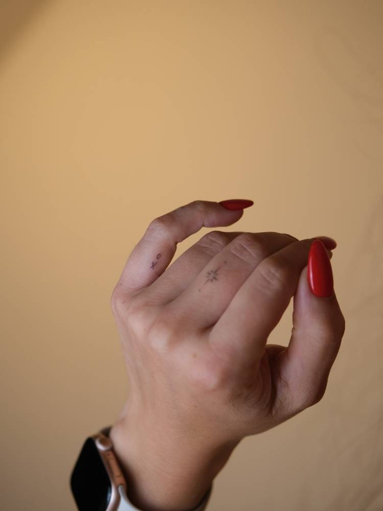 "XO" and north star tattoos located on the fingers.
