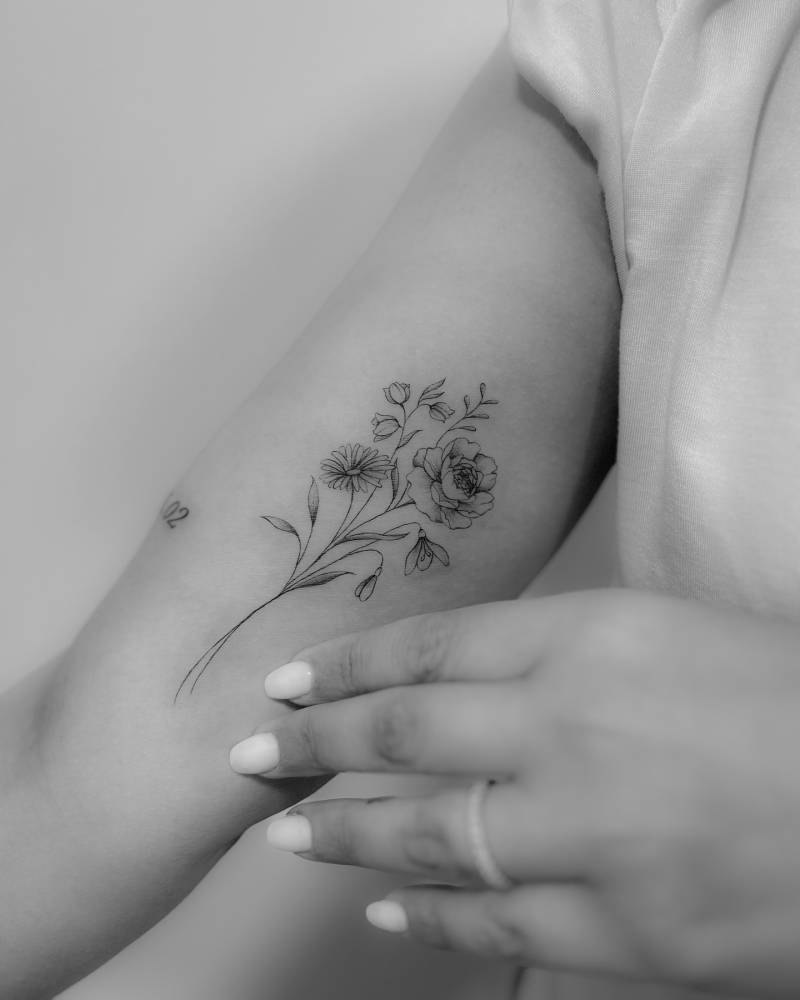 Flower bouquet tattoo in illustrative style located on the inner arm.