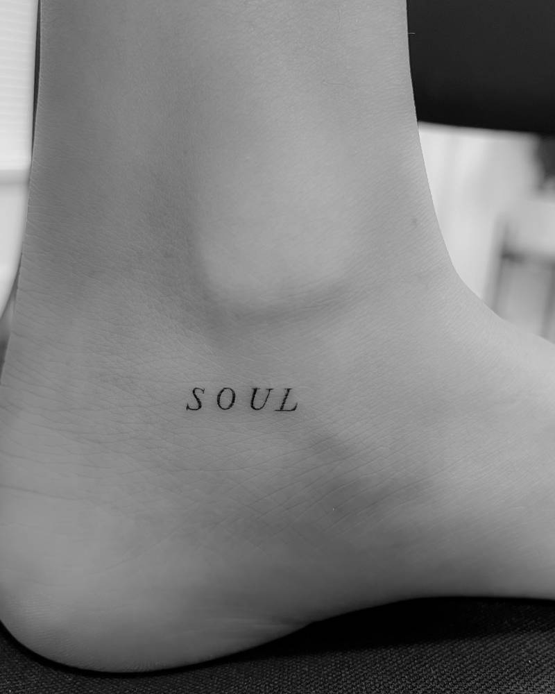 Little word "soul" in serif font tattooed on the ankle.