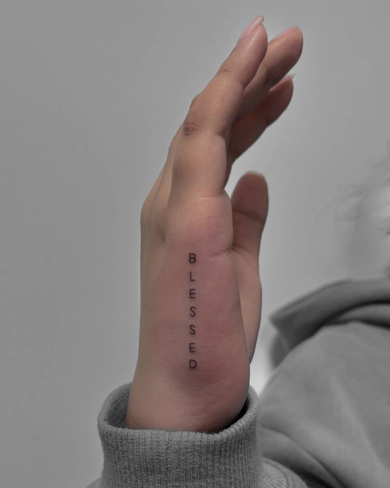 Word "blessed" tattooed on the hand.