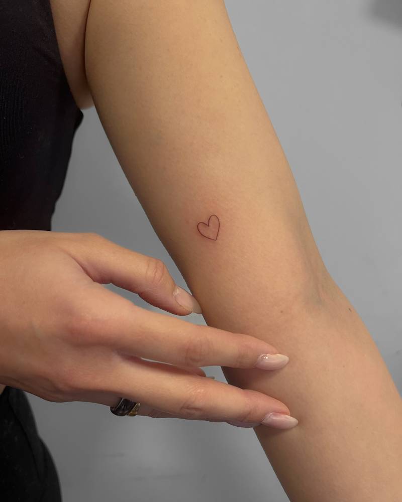 Tiny minimalistic heart tattoo located on the inner arm.