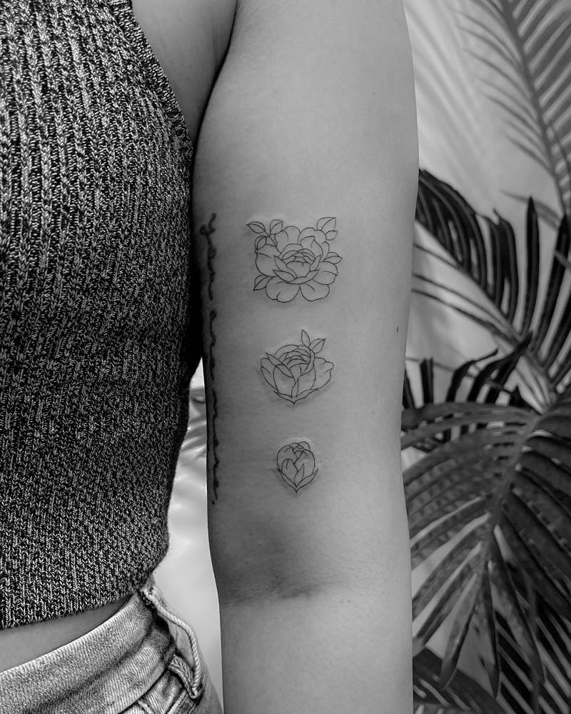 Blooming peony tattoo in fine line style done on the bicep.