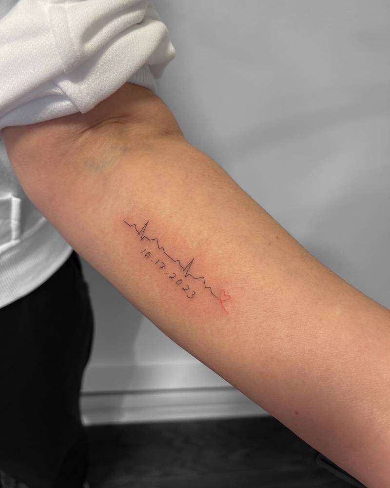Heartbeat and date tattoo located on the inner forearm.