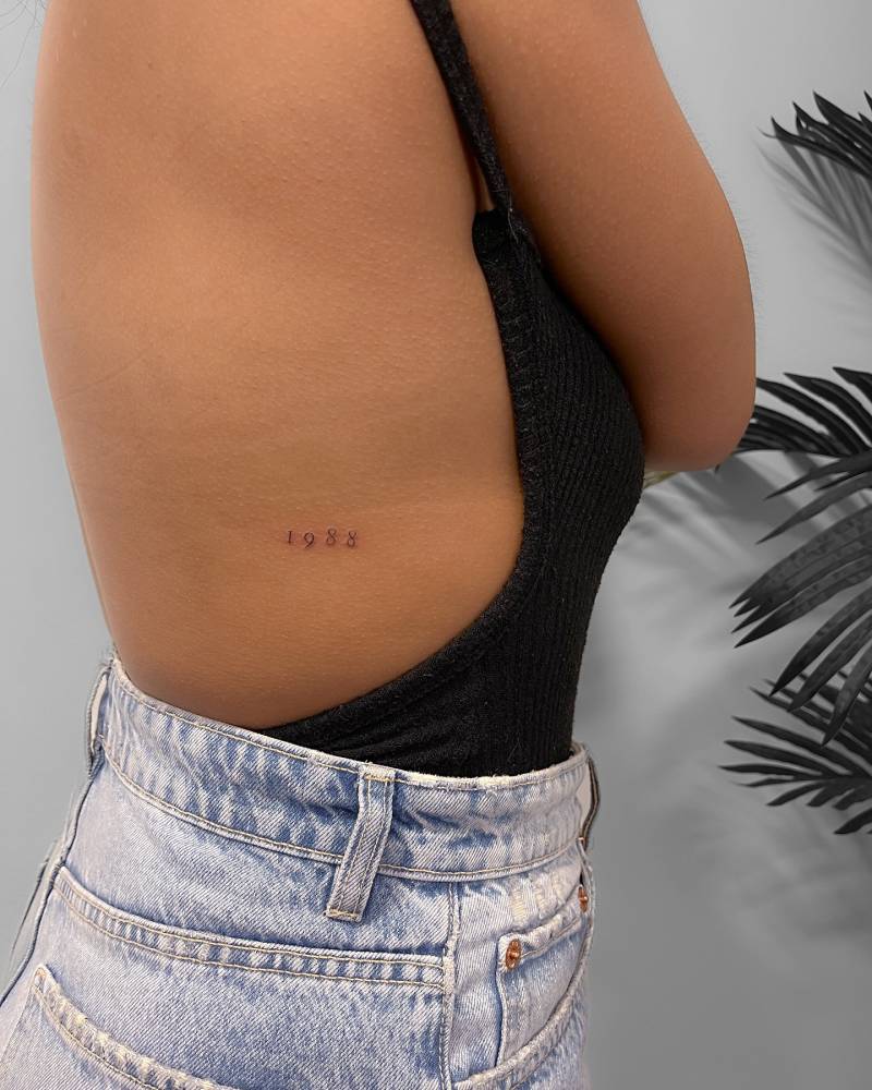 Lettering tattoo of the birth year "1988" located on the rib.