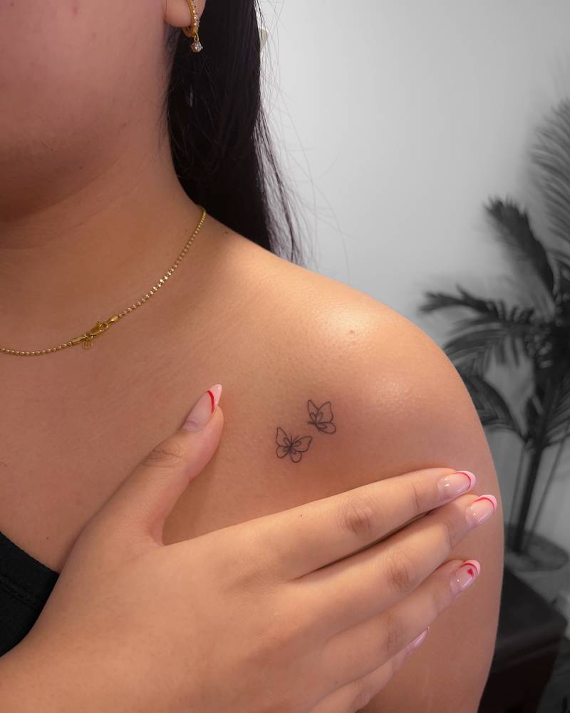 Little butterfly couple tattoo located on the shoulder, done in fine line style.