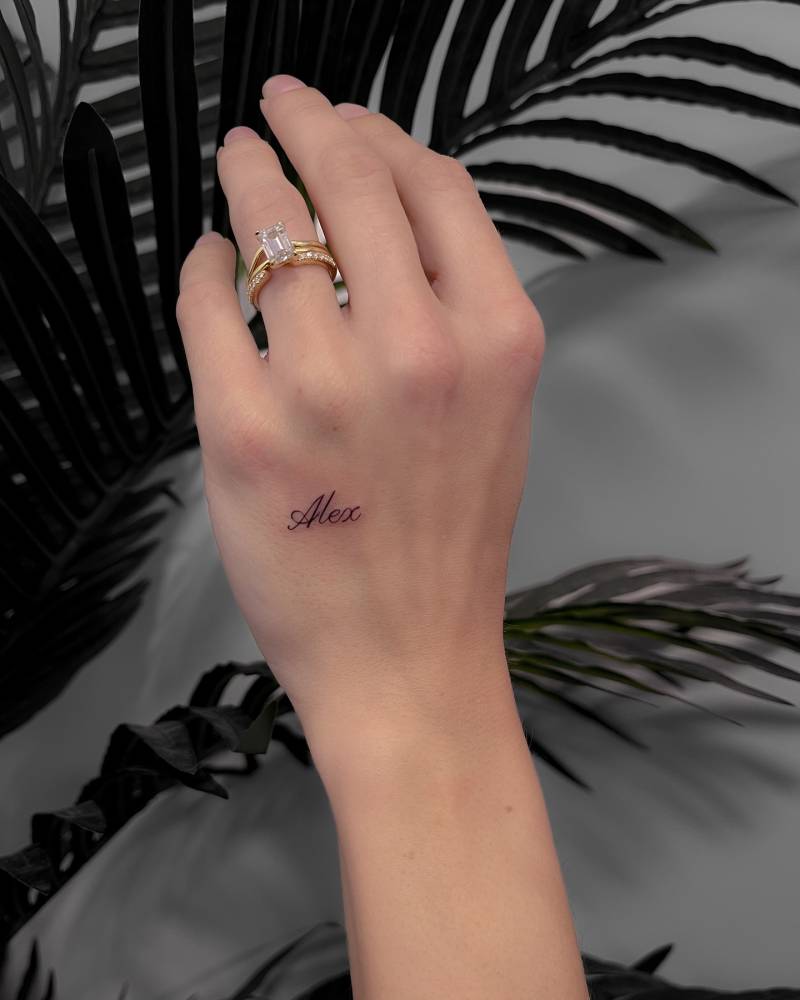 Lettering tattoo of the name "Alex" located on the hand.