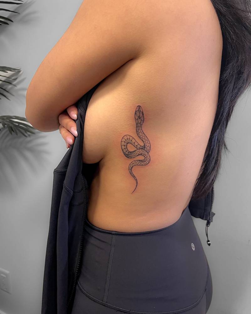 Snake tattoo in illustrative style placed on the side boob.