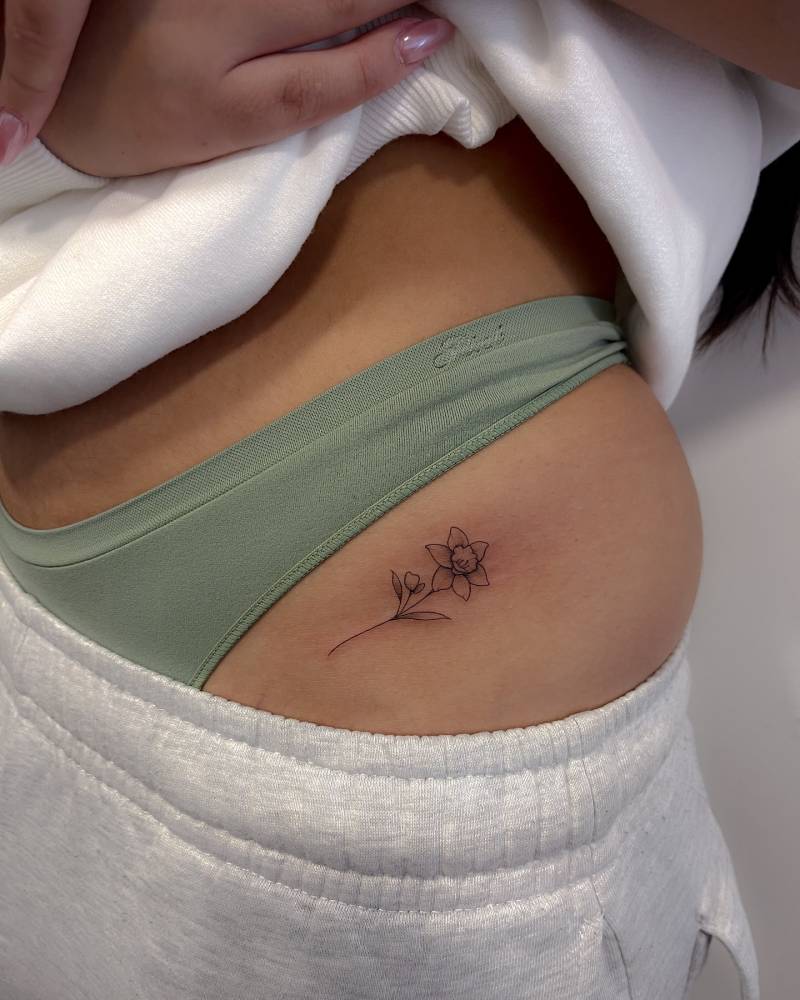 Daffodil tattoo in illustrative style done on the pelvis.