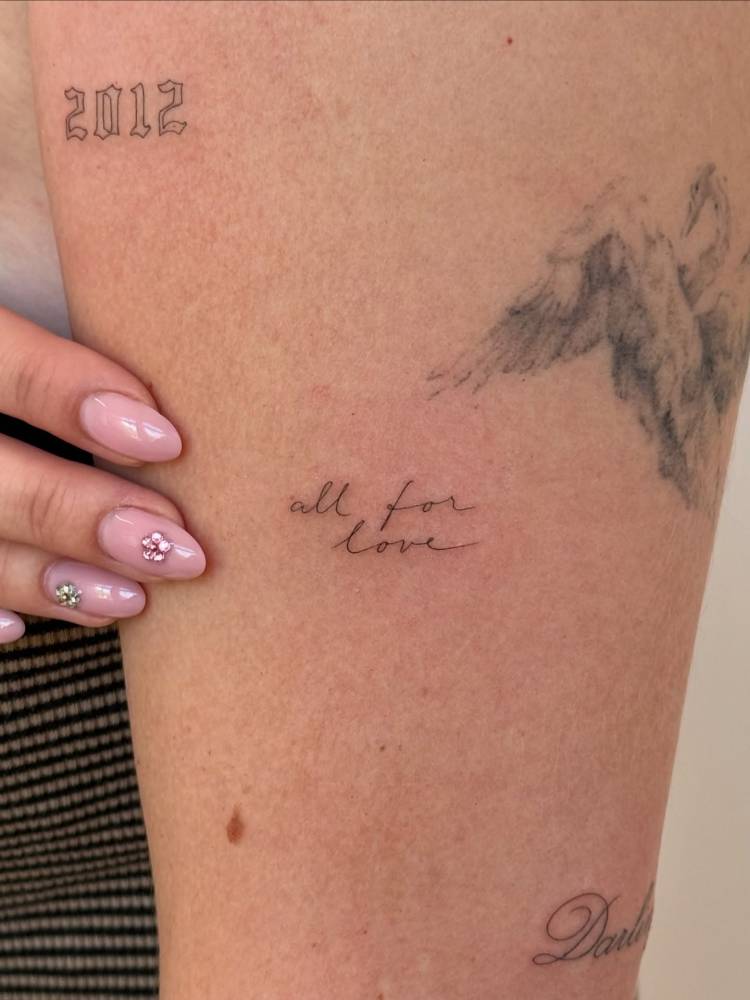 "All for love" handwritten lettering tattoo placed on the upper arm.