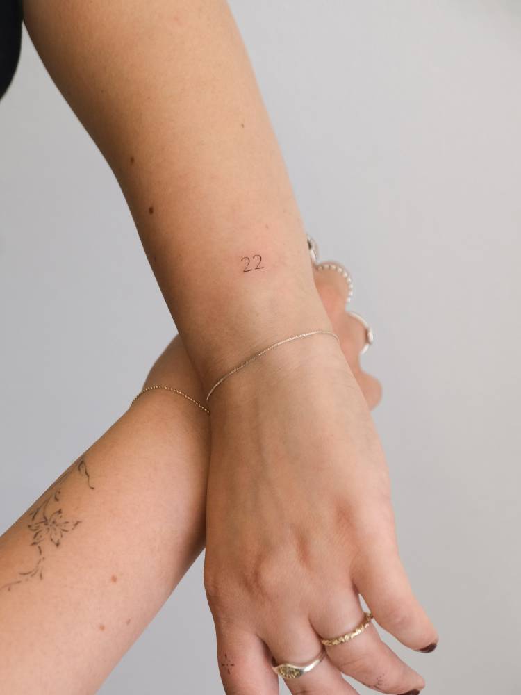 Tiny tattoo of the number "22" located on the wrist.