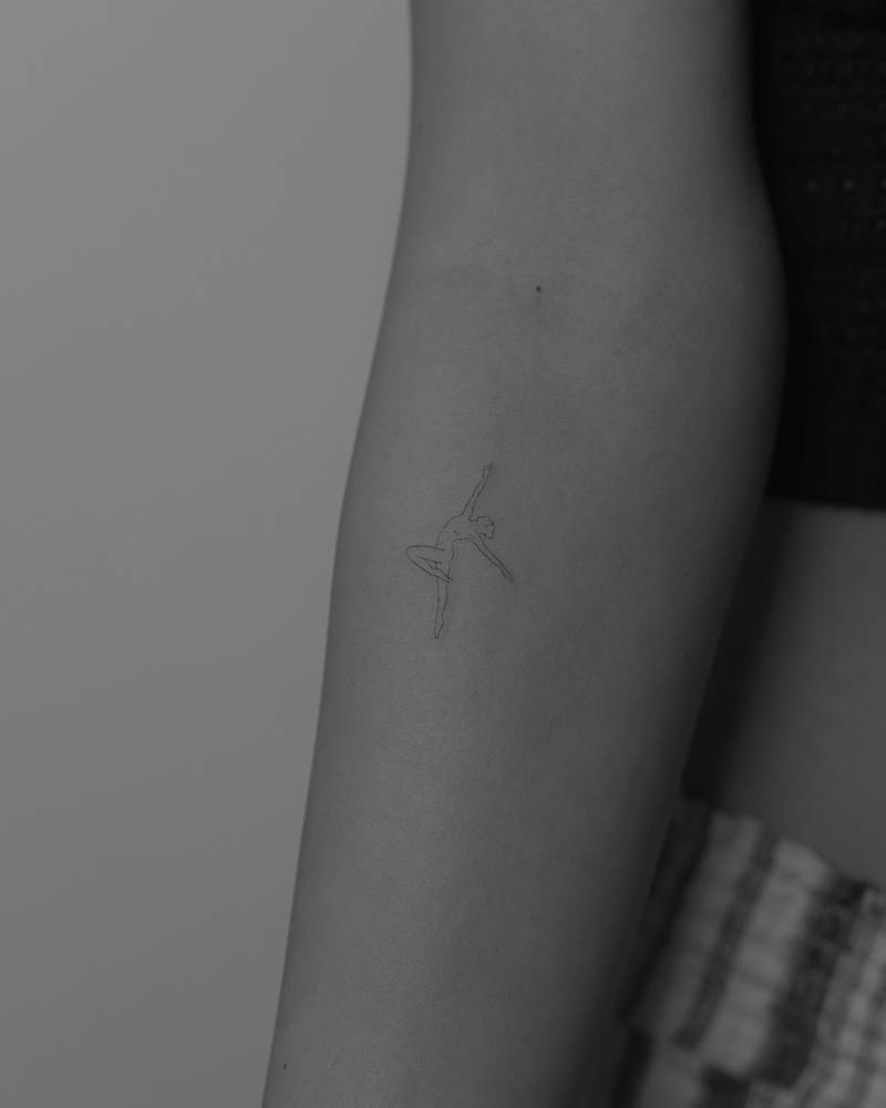 Fine line style nude dancer tattoo located on the inner forearm.