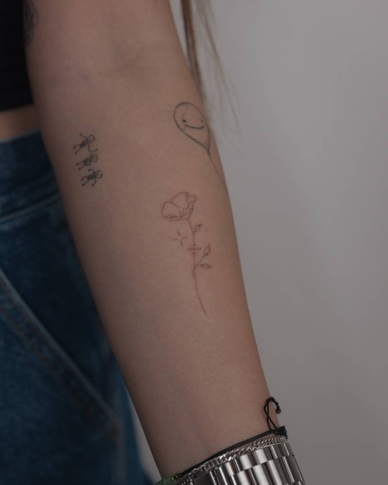 Fine line style poppy flower tattoo located on the inner forearm.