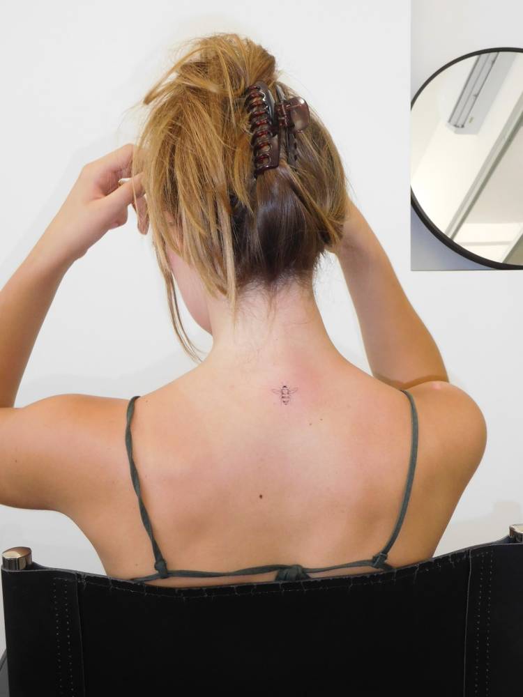Single needle bee tattoo located on the upper back.