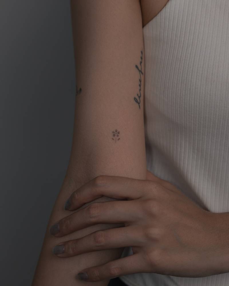 Minimalistic micro flower tattoo located on the inner arm.