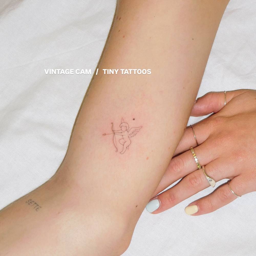 Cupid tattoo in fine line style located on the inner arm.