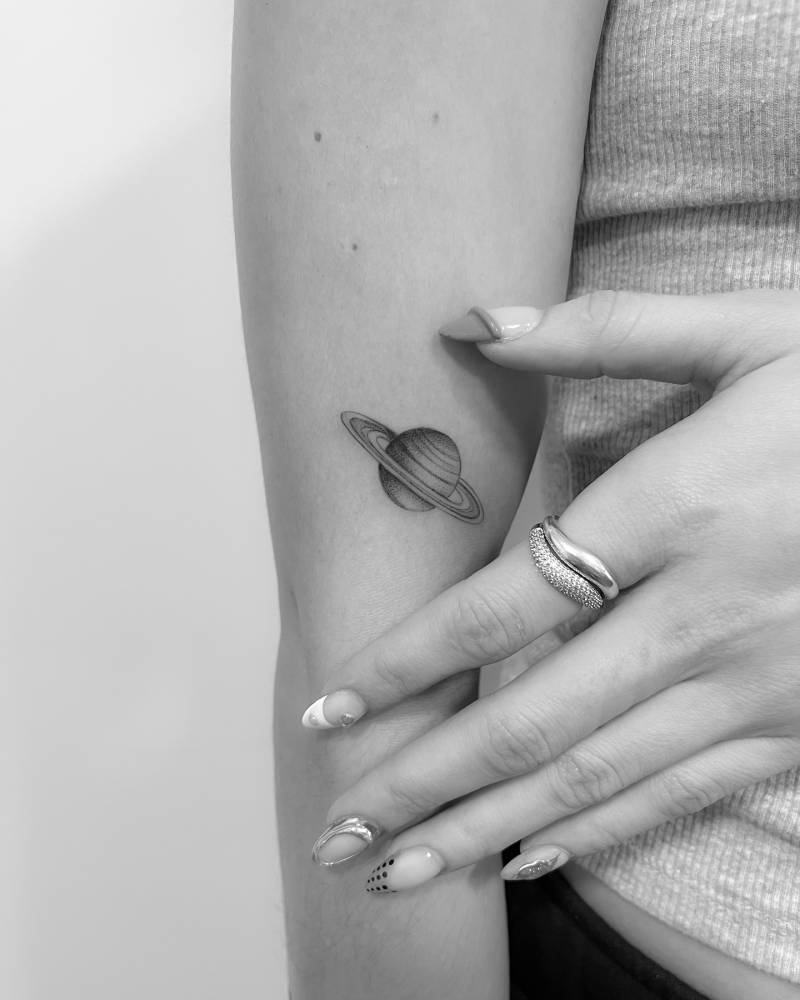 Saturn tattoo in illustrative style located on the upper arm.