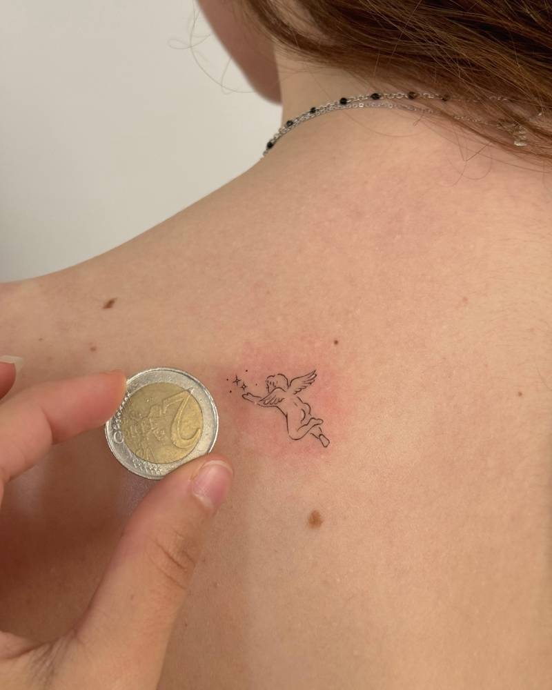 Tiny cherub tattoo in fine line style done on the shoulder blade.