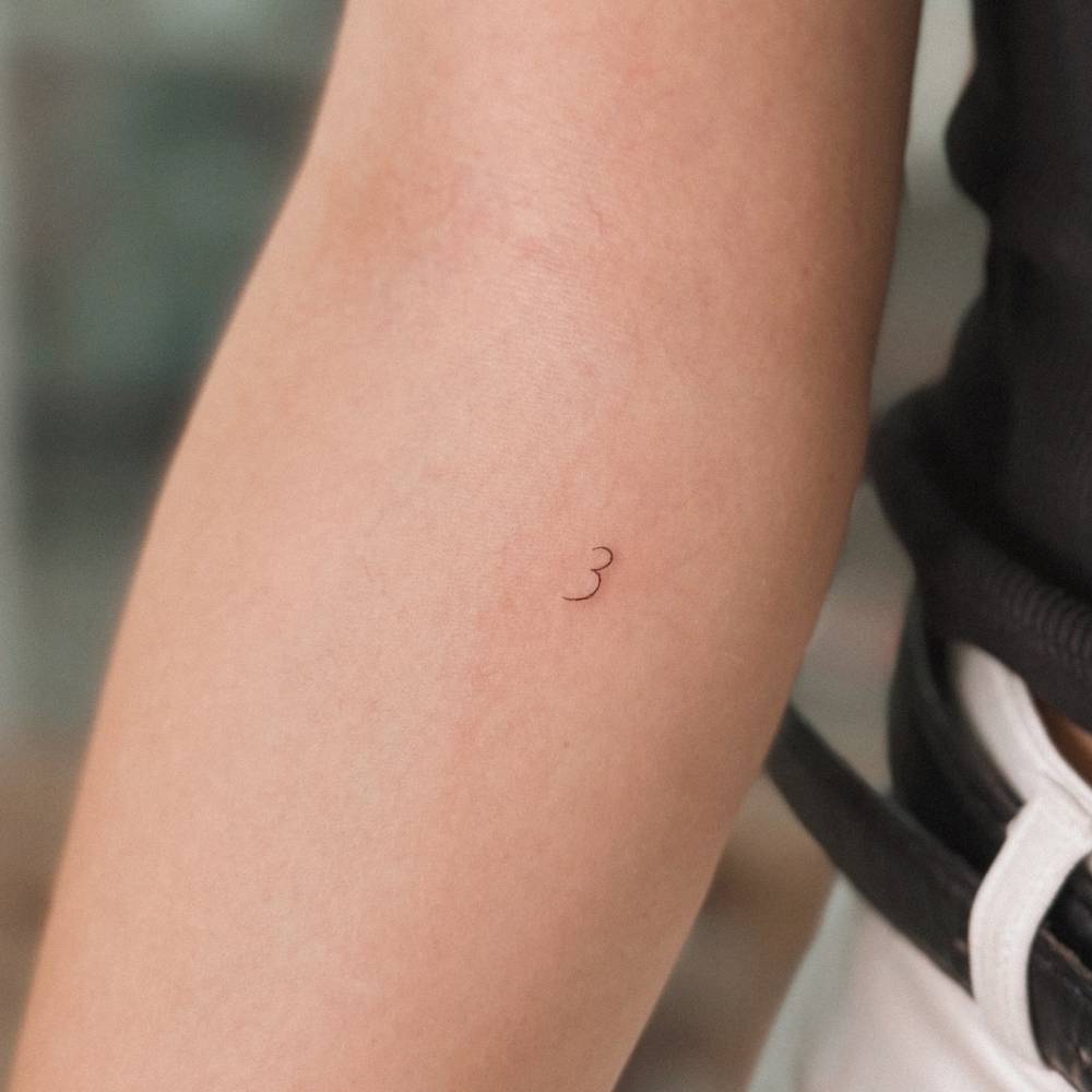 Tiny tattoo of the number "3" located on the inner forearm.