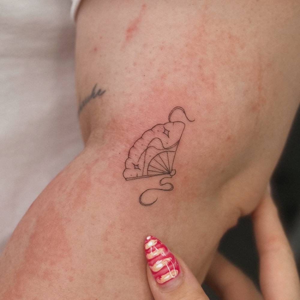 Hand fan tattoo located on the elbow, done in fine line style.
