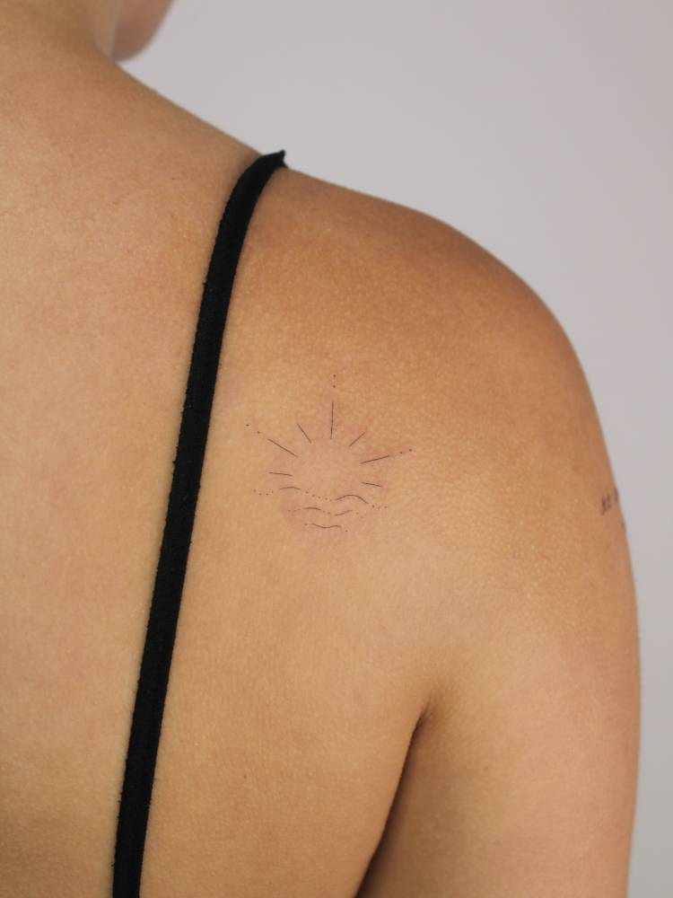 Sea sunset tattoo in minimalistic style done on the shoulder blade.