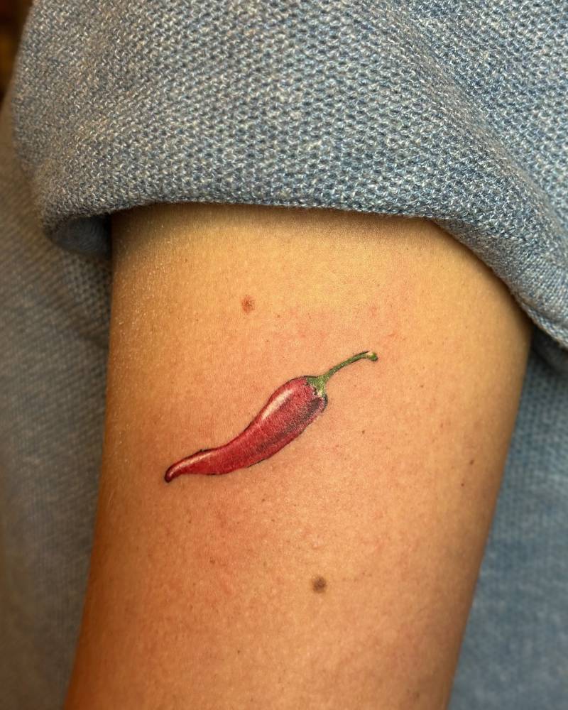 Illustrative style red chili tattoo located on the upper arm.