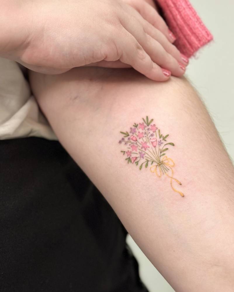 Flower bouquet tattoo in illustrative style located on the inner forearm.