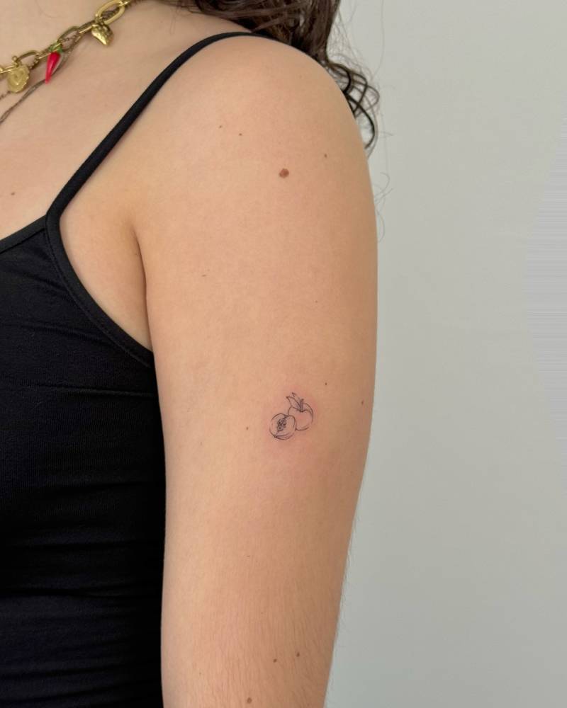 Peach tattoo placed on the upper arm, done in fine line style.