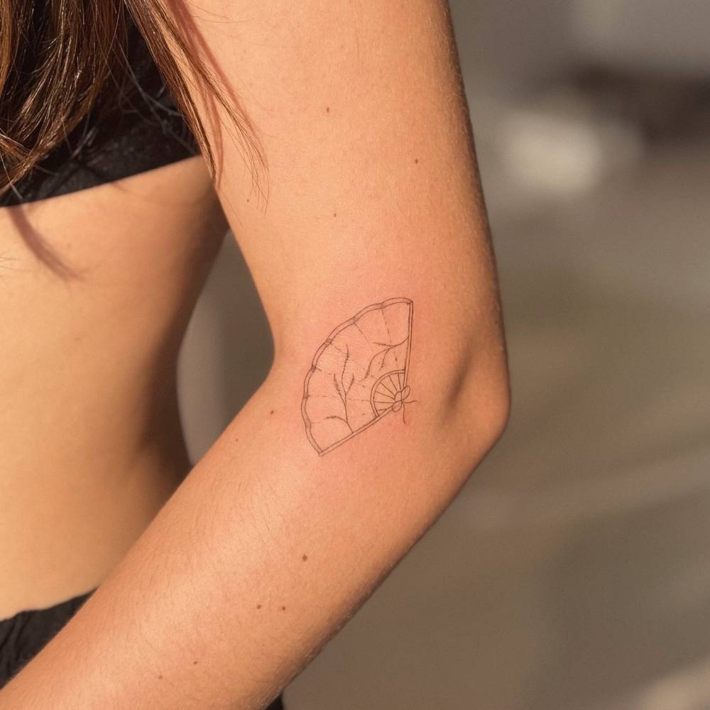 Hand fan in fine line style tattooed on the elbow.